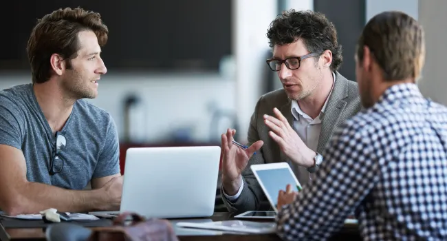 group of men talking with laptops 