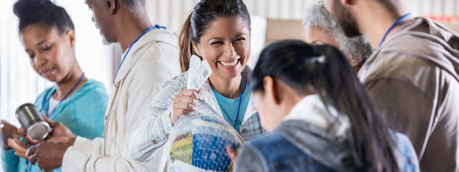 woman handing another woman a wrapped turkey with other people around her smiling