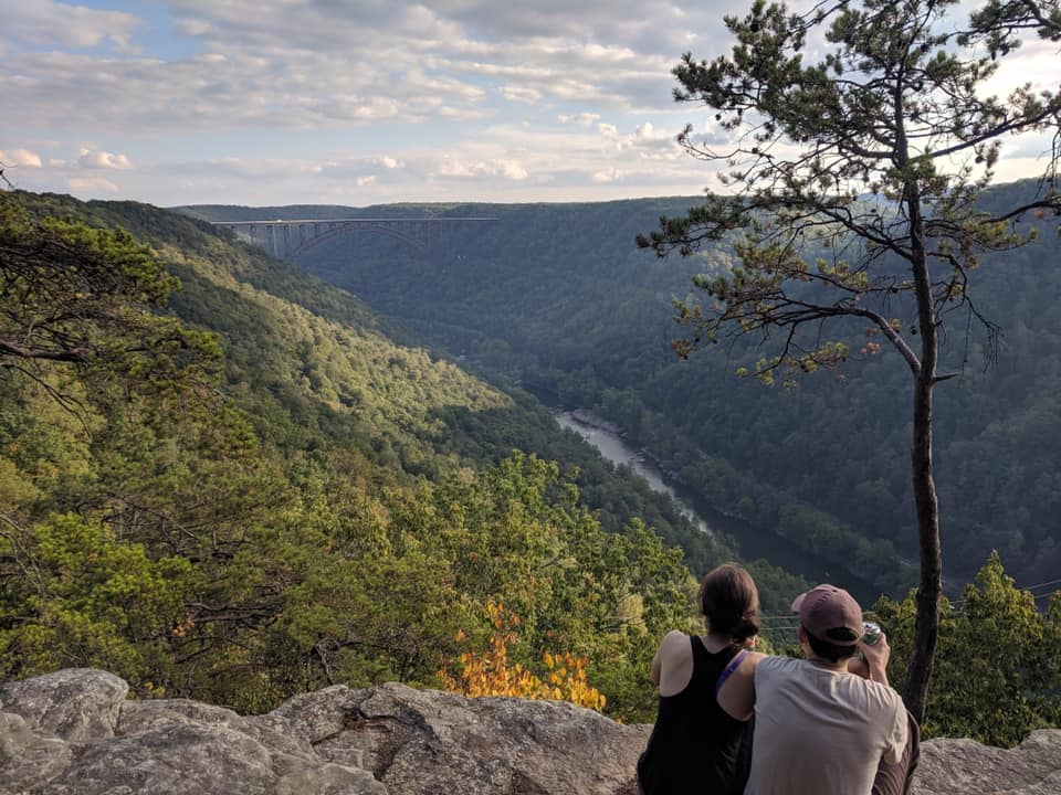 couple sitting an an overlook of the new river gorge in west virginia