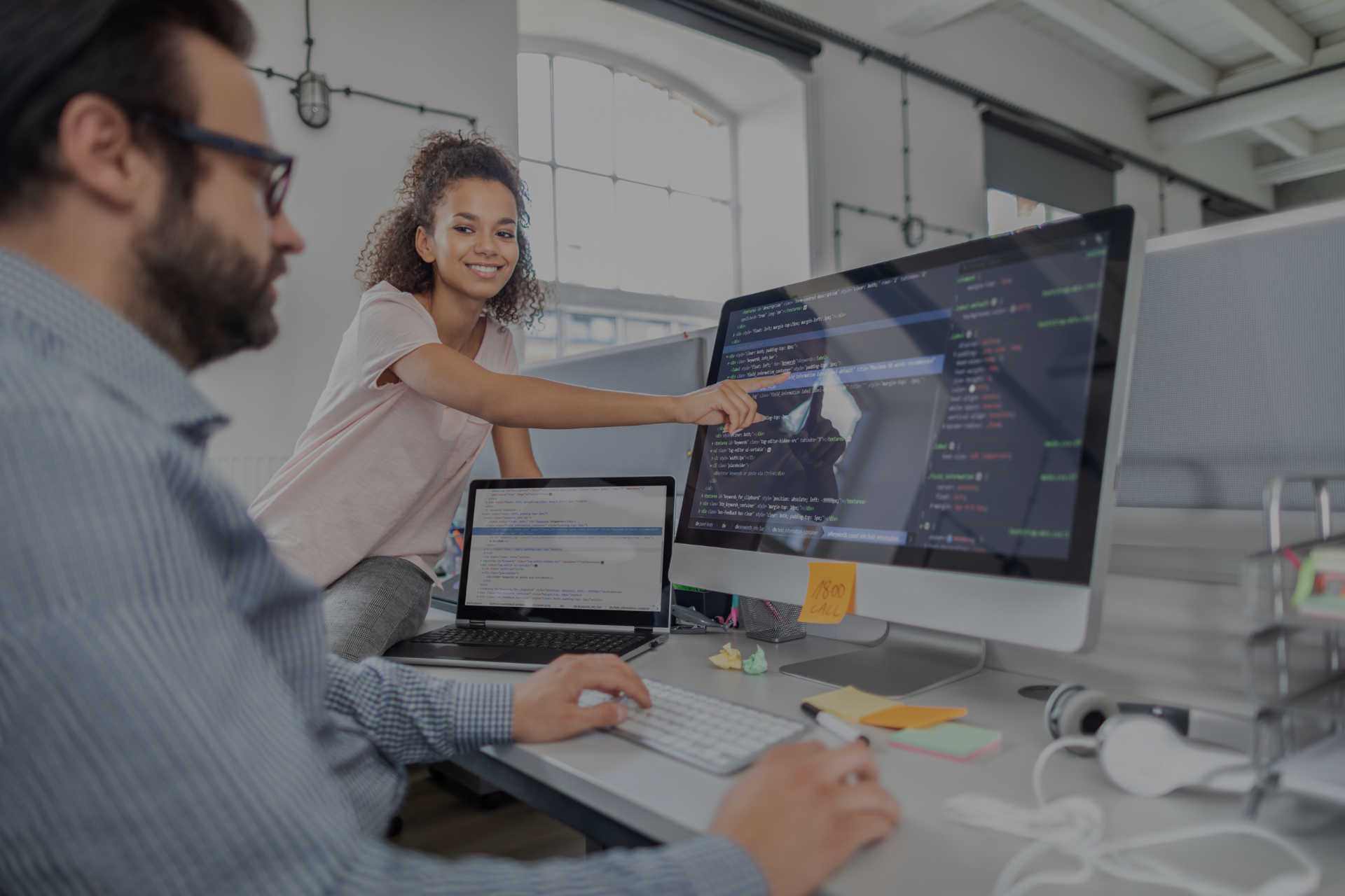 woman pointing at computer screen where developer is coding