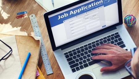 job application on laptop at a desk with glasses and pens